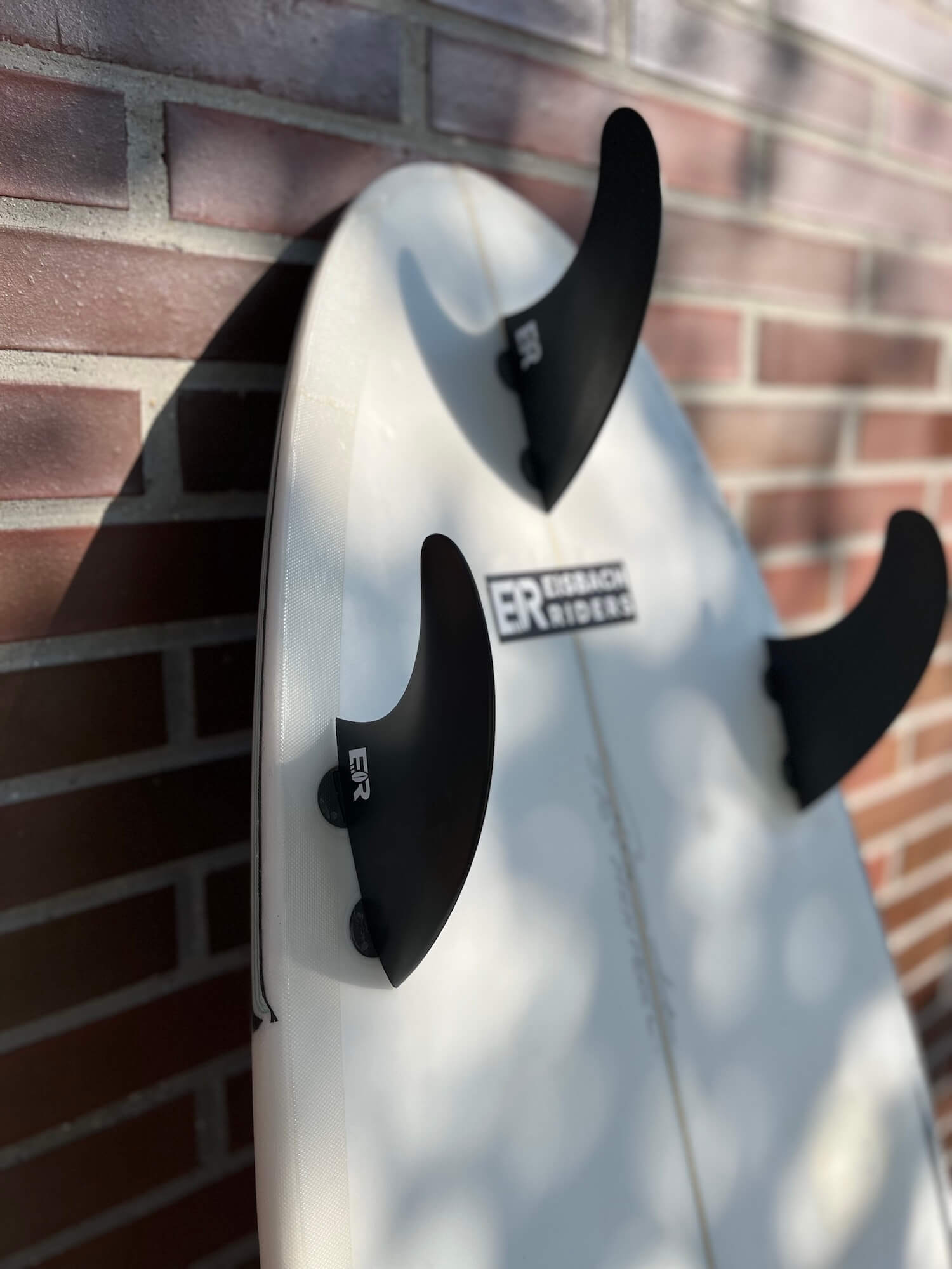 Set of three surf fins on a surfboard — thruster, quad and twin setups compared